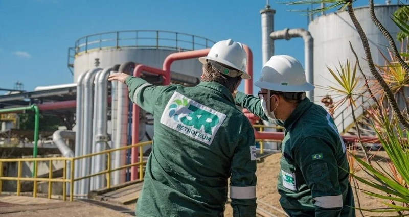 Trabalhadores da 3R Petroleum com tanques ao fundo